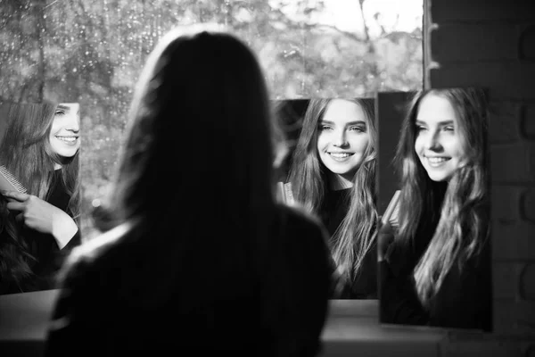 Meisje met lang haar blik op spiegel met kam — Stockfoto