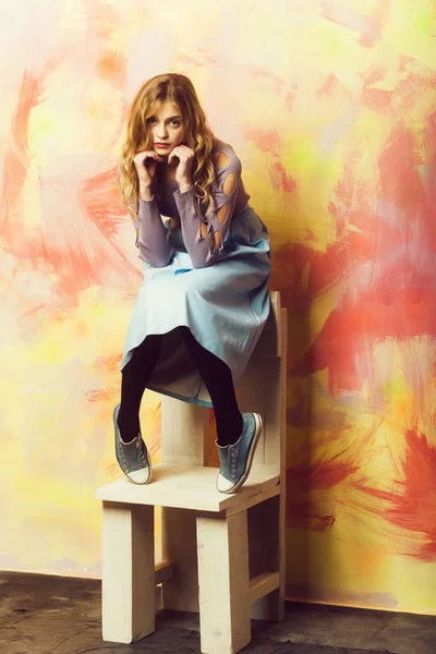 Menina bonita em saia azul e tênis na cadeira de madeira — Fotografia de Stock