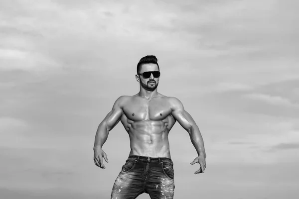 Homme sexy avec corps musclé dans les lunettes de soleil sur le ciel bleu — Photo