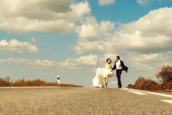 Casamento casal feliz correndo na estrada — Fotografia de Stock