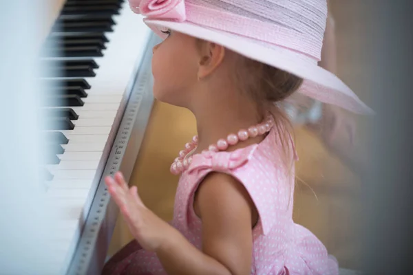 Kind mit rosa Hut, Kleid, Perlenkette an der Tastatur — Stockfoto