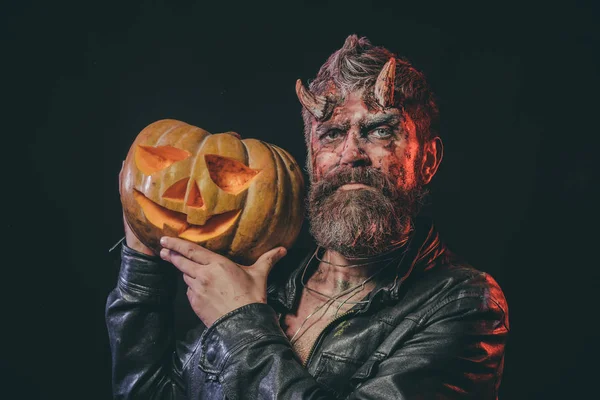 Halloween hombre demonio mantenga calabaza sobre fondo negro — Foto de Stock