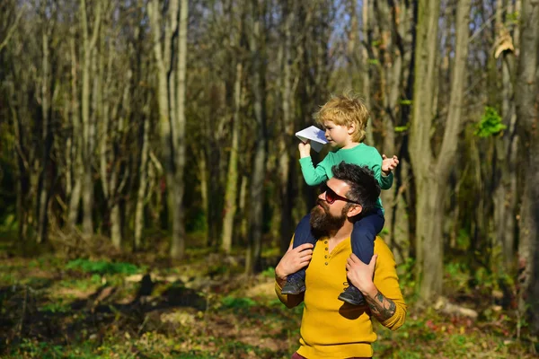 Il piacere è un cammino verso la gioia. Padre dare piccolo bambino a cavalluccio in piacere parco. Padre e figlio passano del tempo insieme — Foto Stock