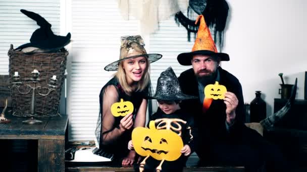 Père, mère et leur fils en costumes de sorcières, de sorcières et de squelettes tiennent le melon dans leurs mains et célèbrent la fête d'Halloween. Fête d'Halloween et concept de célébration . — Video