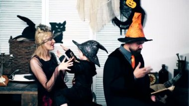 Anne ile Cadılar takım elbise ve oğlu ile iskelet takım elbise sarılma ve babası witchs takım elbiseli bir kitap ve jestleri eliyle Cadılar Bayramı holiday adlı okur