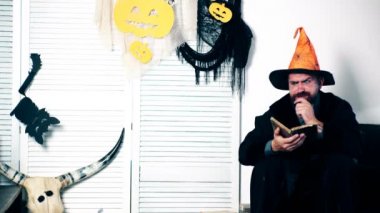 Witchs elbiseli bir adam bir kitap ve jestleri okur. Cadılar Bayramı partisi ve kutlama kavramı. Aile kostümleri Cadılar Bayramı'nda iyi eğlenceler.