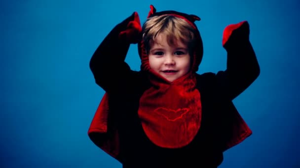 Niño pequeño disfrazado de dragón sobre un fondo azul en unas vacaciones de Halloween. Fiesta de Halloween y concepto de celebración . — Vídeos de Stock