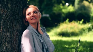 Kız parkta dinleniyor. Bir kız onu laptop ile bir ot yakındaki bir park ağacında oturur. Uzaktan Eğitim