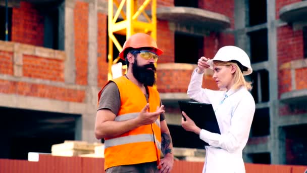 L'ingénieur discute avec l'entrepreneur du calendrier des travaux de construction. Le travail des ingénieurs sur le chantier. Concept de construction . — Video