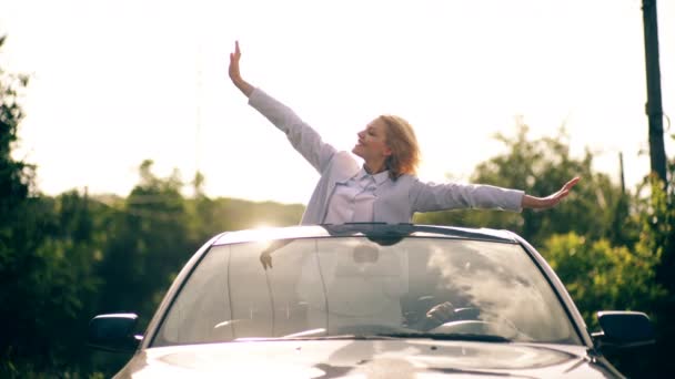 The girl waves her hands from the cars hatch. Attractive young romantic couple enjoying in ride through the forest. The concept of traveling by car. — Stock Video