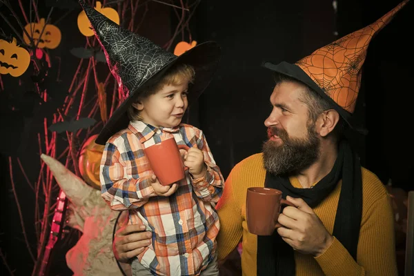 Halloween man and child in witch hat.