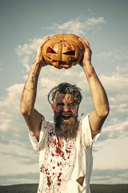 Kabak ek yükü bulutlu mavi gökyüzü üzerinde tutarak Cadılar Bayramı adam