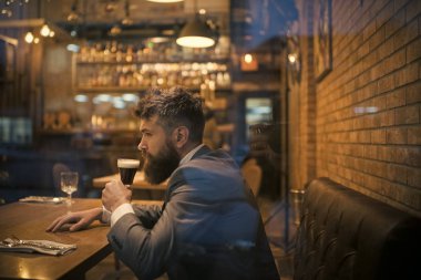 ciddi bar müşteri oturup bira içerken kafede. Bira zamanı. Barda bekleyen hipster tarihi toplantı. Uzun sakal içki puro kulübü ile iş adamı. Sakallı adam dinlenme restoranında bira cam.
