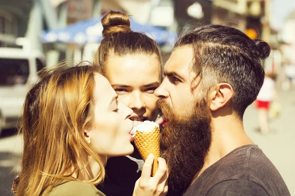 Twee mooie meisjes en brutale, bebaarde man likken ijs — Stockfoto