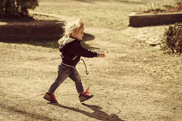 Bambino in giacca blu e jeans cammina con bastone — Foto Stock