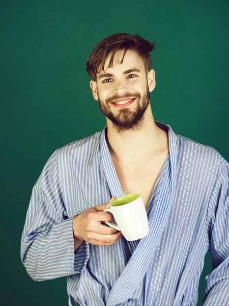 morning of man smiling in blue robe with cup in hand