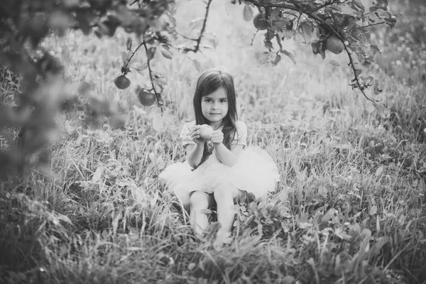 Child girl sitting under apple tree — Stock Photo, Image