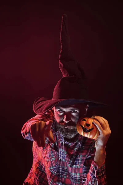 ハロウィン秋の休日のお祝い 暗闇の中でカボチャを保持している魔女の帽子の男 魔法の照明とジャック ランタン 赤い光でひげ人差し指と魔術師 謎と悪夢のコンセプト — ストック写真