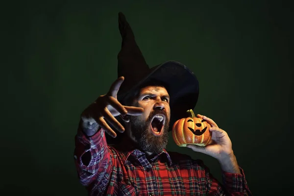 Halloween man in wizard hat holding pumpkin