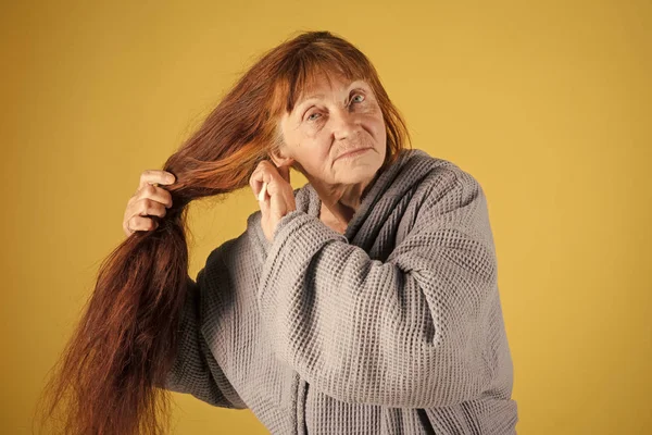 Old lady with hair brush on yellow background. — Stock Photo, Image
