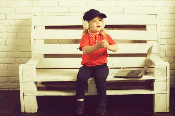 Маленький хлопчик в гарнітурі слухає музику, аудіокнигу, працює на ноутбуках — стокове фото