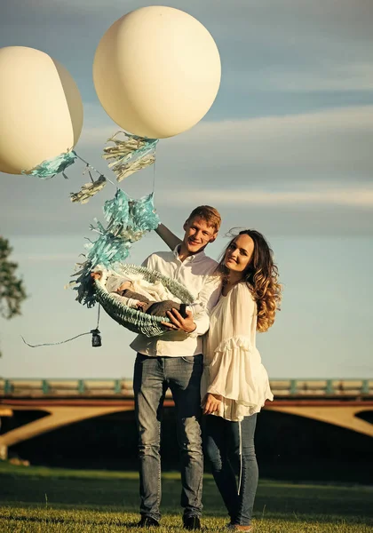 Lycklig familj leende med baby i korg med air ballonger — Stockfoto