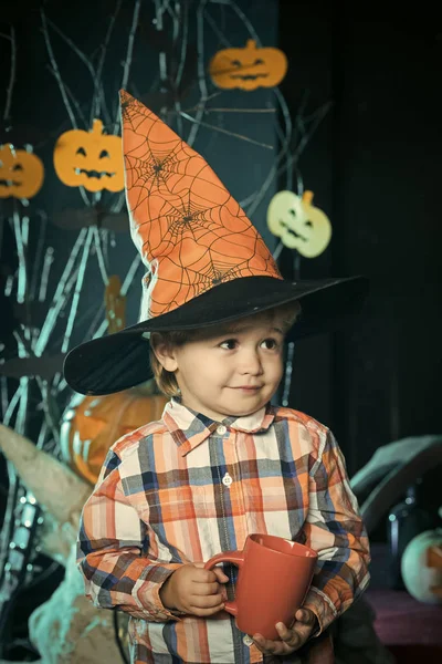 Halloween kleine jongen drinken van thee of melk cup. — Stockfoto