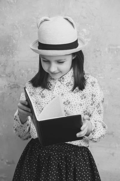 Adorável menina lendo livro nota preta — Fotografia de Stock