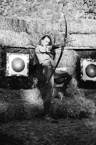 Young archer girl with bow near hay with target — Stock Photo, Image