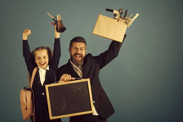 Kind en tutor houden schoolbenodigdheden en blackboard — Stockfoto