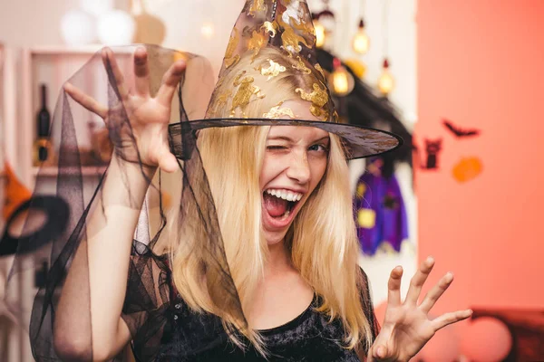 Belle femme surprise en chapeau et costume de sorcières. Portrait de femme Halloween. Sorcière d'Halloween avec une citrouille sculptée et des lumières magiques dans une pièce sombre. Concept de personnes d'Halloween . — Photo