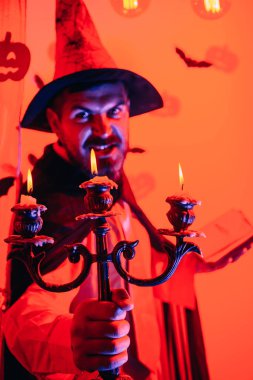 Cadılar Bayramı için peri masalı arka planında büyücü kostümlü yakışıklı bir adam. Cadılar Bayramı, bayram kutlaması. Cadılar Bayramı arka planında komik bilge sihirbaz.