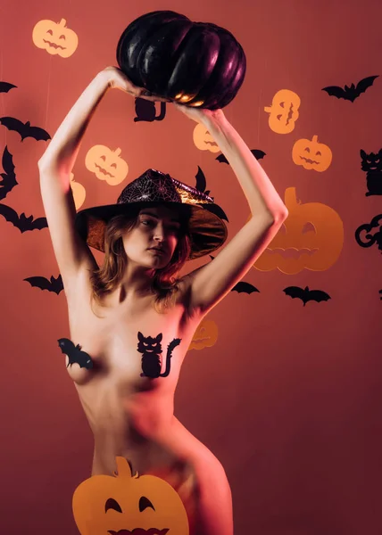 Mujer sexy en el fondo de Halloween. Sexy mujer vestida con fondo de Halloween. El caramelo más popular para Halloween. Cabeza de calabaza de Halloween Jack linterna con velas encendidas. Calabaza mágica. — Foto de Stock