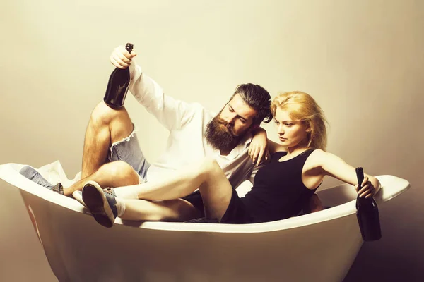 Молодая пара в ванной с бутылками вина — стоковое фото