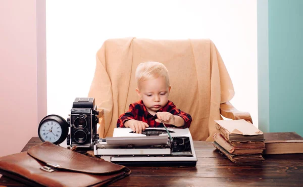 Kleine jongen secretaris type papier op de oude schrijfmachine op Bureau. Kind leren typen op retro typemachine in kantoor — Stockfoto