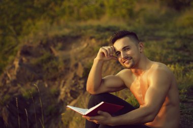 Kitap açık ile gülümseyen kaslı adam