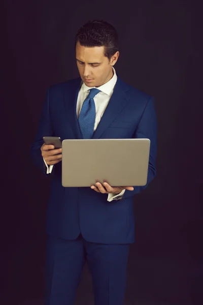 Бізнесмен використовує мобільний телефон під час роботи на ноутбуці — стокове фото