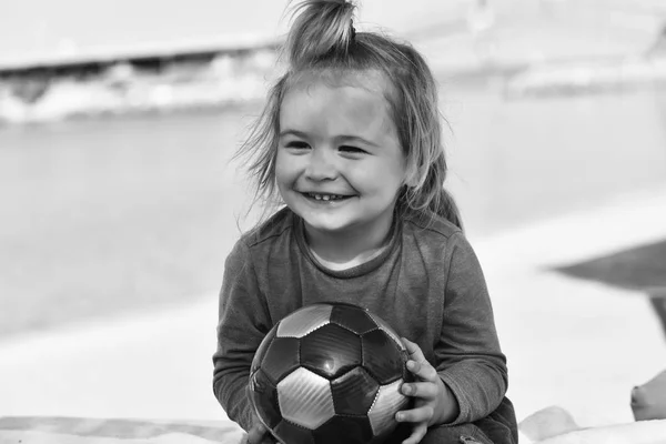 Małe dziecko uśmiechnięty chłopiec z długimi blond włosami, trzymając piłkę — Zdjęcie stockowe