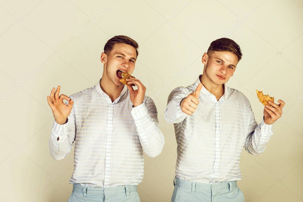 Men eating buns on grey background