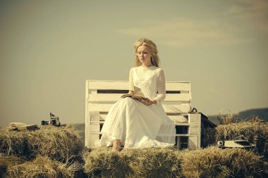 Kadın mavi gökyüzü bankta kitap okuma