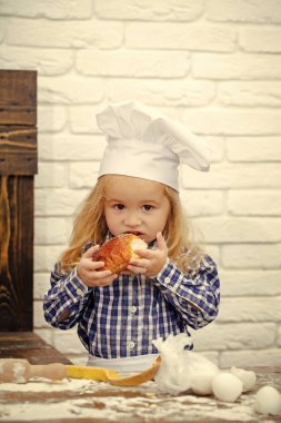 Beyaz tuğla duvara ekmek çörek yiyen çocuk