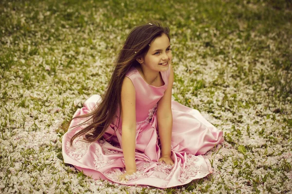 Menina na grama verde com pétalas — Fotografia de Stock