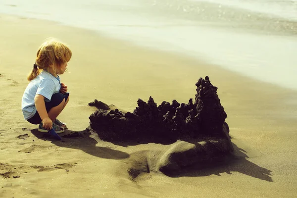 かわいい男の子海のビーチで砂の城を構築します。 — ストック写真