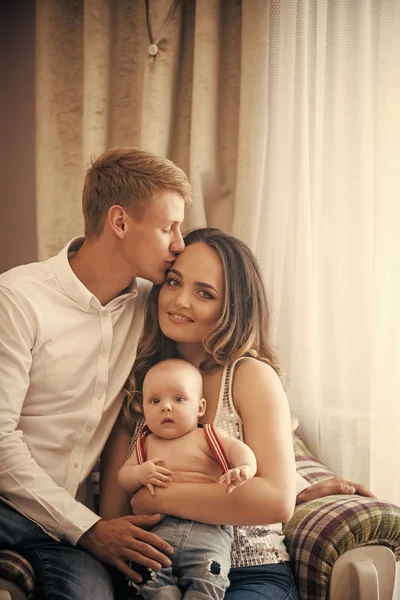Padre beso madre con bebé hijo en sillón —  Fotos de Stock