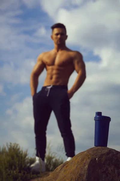 Hombre musculoso posando cerca de botella de agua — Foto de Stock