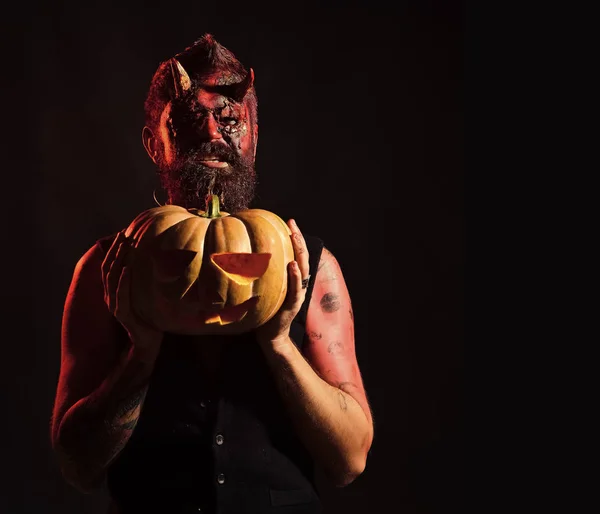 Halloween uomo diavolo tenendo zucca su sfondo nero — Foto Stock