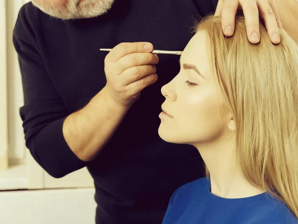 Mujer consiguiendo maquillaje en la cara con cepillo en mano masculina — Foto de Stock