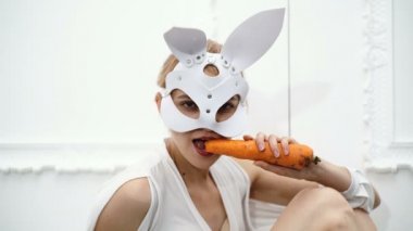 Kadının tavşan havuç yemek maskeli kapatın. Cadılar Bayramı partisi ve kutlama kavramı. Kavram deri maske Bdsm.