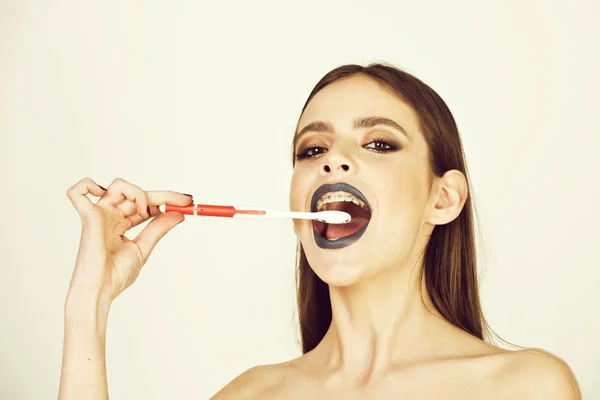 Chica con dientes frenos y cepillo, tiene maquillaje de moda —  Fotos de Stock