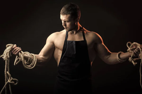 Muscular man in apron with rope — Stock Photo, Image